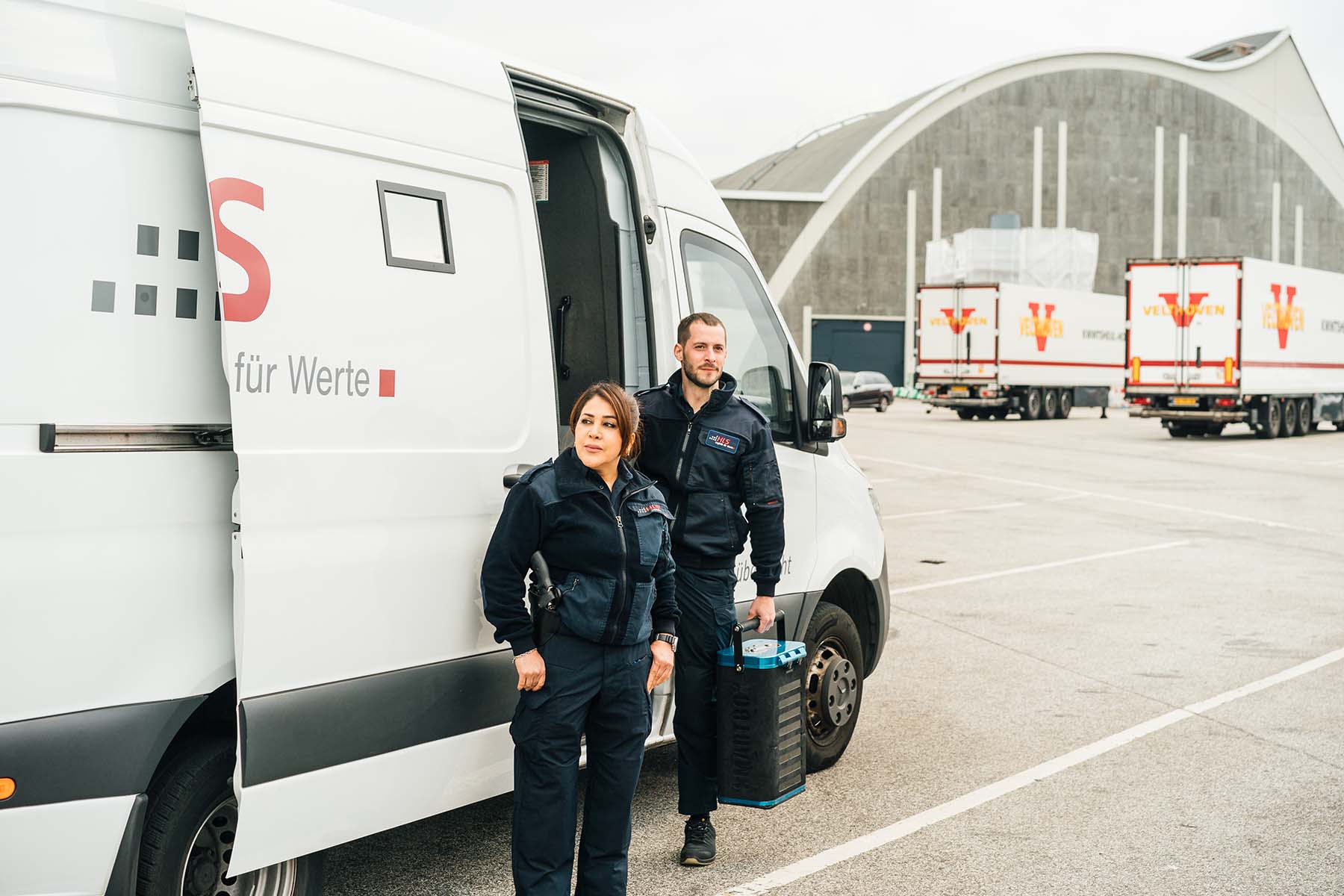 Teammitglieder am Geldtransporter auf einem Logistikgelände